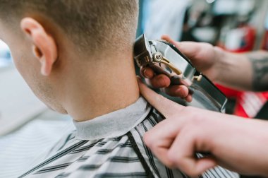 Yakın çekim. Kırpıcı ile el, müşterinin boynundaki kılları keser. Saç stili yaratmak için kırpıcıyla çalışmak. Geçmişi. Berber konsepti. Boşluğu kopyala