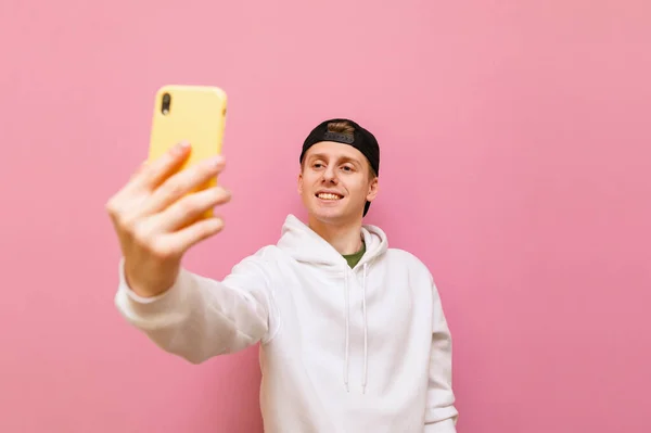 Улыбающийся Молодой Человек Стоит Розовом Фоне Делает Видеозвонок Смартфоном Руках — стоковое фото