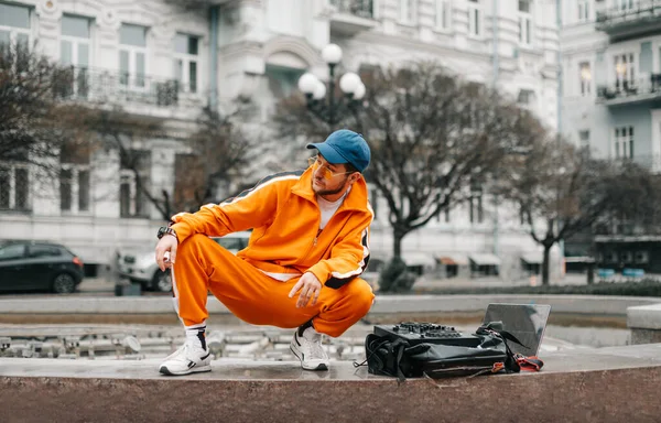 Modieuze Jongeman Casual Kleding Zit Met Laptop Muziekmixer Luidspreker Straat — Stockfoto