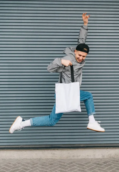 Счастливый Молодой Человек Стильной Повседневной Одежде Прыгает Сером Фоне Стены — стоковое фото