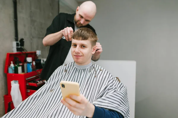 Mannen Klipper Sin Favorit Frisör Herrfrisör Med Smartphone Handen Tittar — Stockfoto