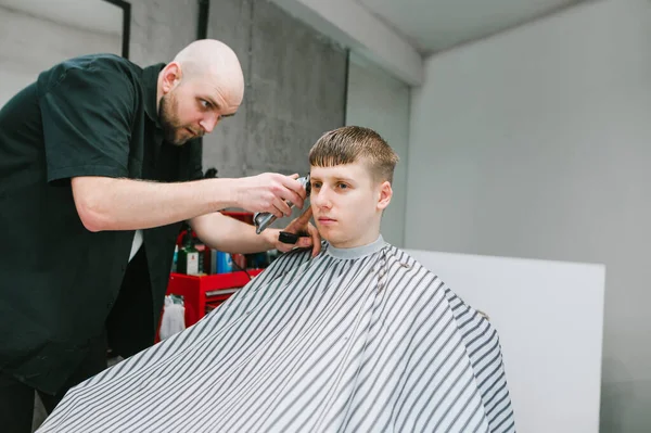 Professioneller Friseur Schneidet Einem Gutaussehenden Jungen Mann Mit Ernstem Gesicht — Stockfoto