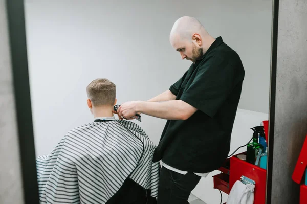 Glatzköpfiger Professioneller Friseur Schneidet Einen Jungen Mann Mit Einem Haarschneider — Stockfoto