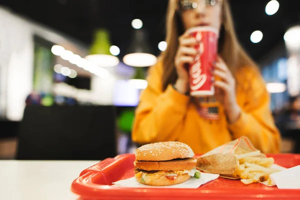 Hamburgeres Tálca Sült Krumplival Lány Hátterében Gyorskajáldában Ülve Piros Üvegből — Stock Fotó