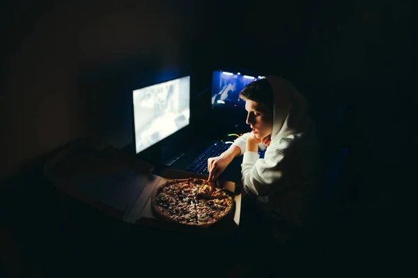 Νεαρός Κάθεται Νύχτα Ένα Γραφείο Έναν Υπολογιστή Και Τρώει Πίτσα — Φωτογραφία Αρχείου