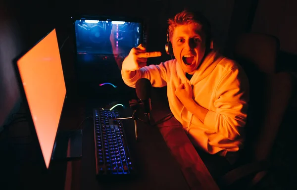 Emotional Young Male Gamer Headphones Sits Desk Red Screen Computer — Stock Fotó