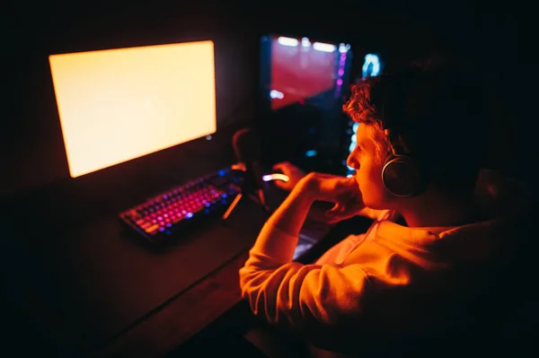 Фото Игрока Спины Сидящего Компьютером Играющего Видеоигры Смотрит Красный Экран — стоковое фото