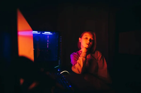 Atrakcyjna Graczka Siedzi Przy Komputerze Domu Pozuje Kamery Czerwonym Świetle — Zdjęcie stockowe
