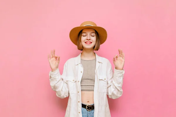 Atraktivní Dívka Letních Šatech Klobouku Medituje Růžovém Pozadí Zvednutýma Rukama — Stock fotografie