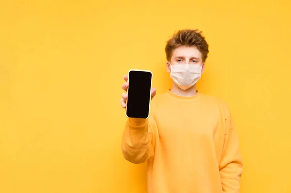 Young Man Medical Mask Shows Smartphone Black Screen Camera Orange — Stock Photo, Image