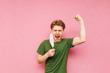 Mutlu genç adam pembe bir arka planda yüzündeki tıbbi maskeyi çıkarıyor, kameraya bakıyor ve elini kaldırarak seviniyor. Coronavirus 'a karşı zafer. Salgın. Karantinaya alın. covid-19.