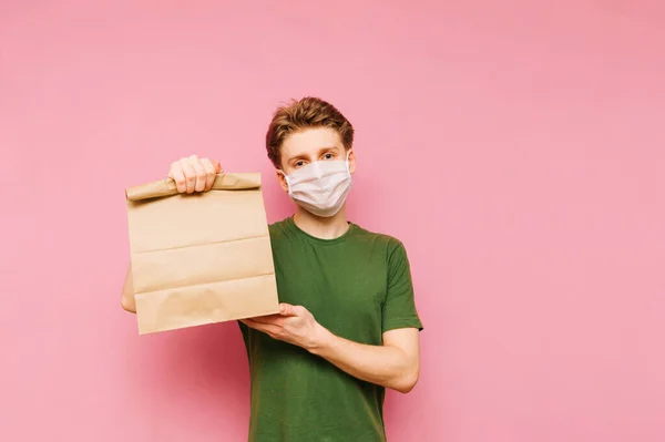 Happy Young Man Protective Mask Stands Pink Background Holds His — Stock Photo, Image