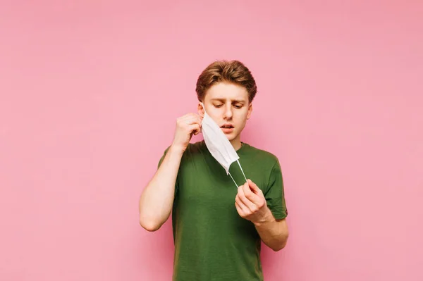 Молодой Человек Снимает Маску Лица Розовом Фоне Парню Надоело Носить — стоковое фото