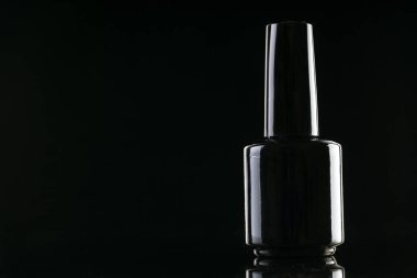 Siyah arka planda siyah tırnak cilası olan küçük şişe.