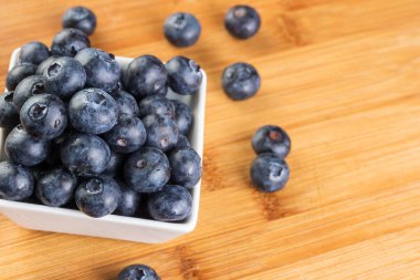 Beyaz tabakta güzel taze yaban mersini. Ahşap arka planda fotoğraflanmış.