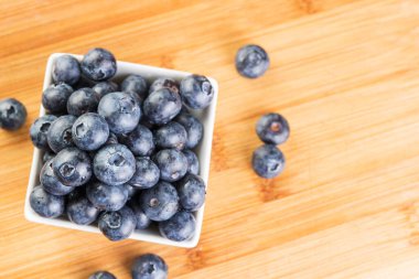 Beyaz tabakta güzel taze yaban mersini. Ahşap arka planda fotoğraflanmış.