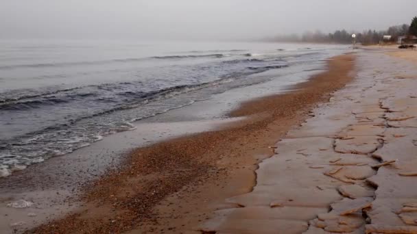 Morning fog on the lake in the fall. Sandy shore covered with ice. — Stock Video