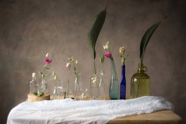 Tablo, gri duvar arka plan üzerinde cam şişelerde pembe güller