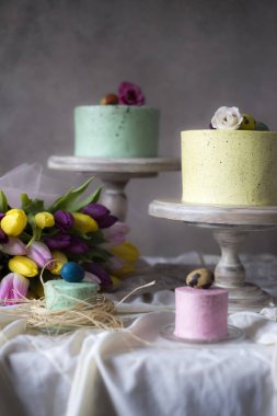 Paskalya masa dekorasyonu, bahar çiçekleri ve tatil masada boyalı yumurta ile renkli ev yapımı kek 
