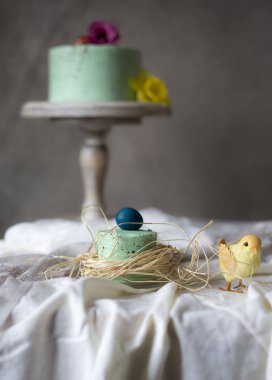 Boyalı yumurta Paskalya mini kek kuru otların arasında sarılmış, tatil tablo arka plan bulanık