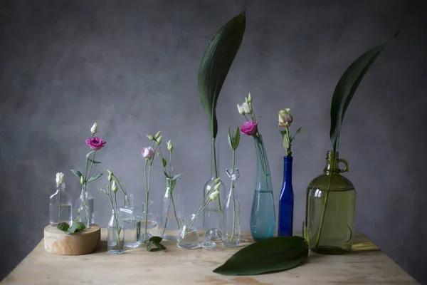 Розовые Розы Стеклянных Бутылках Столе Серый Фон Стены — стоковое фото
