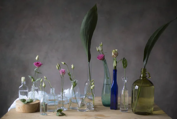 Pink Roses Glass Bottles Table Grey Wall Background — Stock Photo, Image