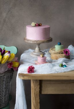 Paskalya masa dekorasyonu, lezzetli ev yapımı kek bahar çiçekleri ve tatil masada boyalı yumurta. Sepeti taze yakın tablo Easter yerleştirilir