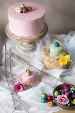 Paskalya masa dekorasyonu, bahar çiçekleri ve tatil masada boyalı yumurta ile lezzetli ev yapımı kekler 