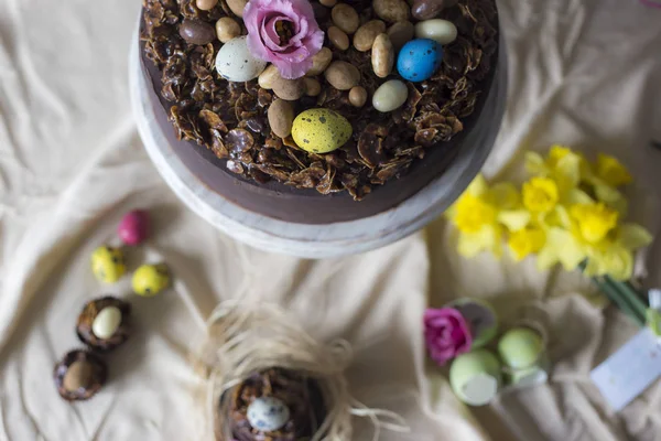 Chocolate cakes for Easter with flowers. Holiday table decoration with Easter cakes,  flowers and colorful eggs