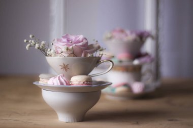 Closeup bardak ve çiçeklerle süslü masada kurabiye