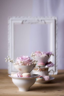 Closeup bardak ve çiçeklerle süslü masada kurabiye