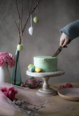 Erkek closeup ev yapımı Paskalya alarak dilim kek dekore edilmiş tatil tablosundan eller