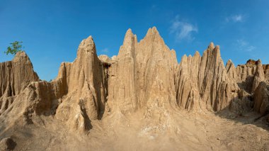 Turuncu toprak sopalar ve mavi gökyüzüne karşı küçük ağaçlar.