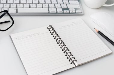 Bilgisayar laptop, fincan kahve, defter ve diğer malzemeleri ile modern beyaz ofis Resepsiyon üst tablo. Beyaz arka plan üzerinde üstten görünüm kopya alanı ile. Üstten Görünüm, düz yatıyordu.