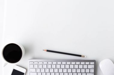 Bir fincan kahve, bilgisayar dizüstü, akıllı telefon ve diğer malzemeleri ile modern beyaz ofis masa üstü tablo. Beyaz arka plan üzerinde üstten görünüm kopya alanı ile. Üstten Görünüm, düz yatıyordu.