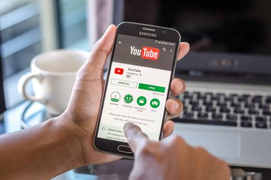 Chiang Mai, Tayland - 1 Şubat 2017: Asya adam Resepsiyon ofis üstünde belgili tanımlık perde üzerinde youtube uygulaması ile Samsung Galaxy S6 tutarak. İş çalışma alanı'nın Üstten Görünüm.