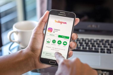 Chiang Mai, Tayland - 1 Şubat 2017: Asya adam instagram app üstünde belgili tanımlık perde Resepsiyon Office ile Samsung Galaxy S6 tutarak. İş çalışma alanı'nın Üstten Görünüm.