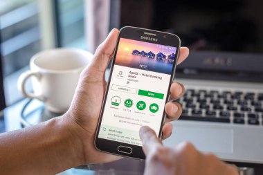 Chiang Mai, Tayland - 1 Şubat 2017: Asya adam agoda app üstünde belgili tanımlık perde Resepsiyon Office ile Samsung Galaxy S6 tutarak. İş çalışma alanı'nın Üstten Görünüm.