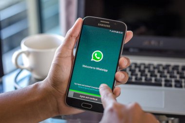 Chiang Mai, Tayland - 1 Şubat 2017: Asya adam whatsapp app üstünde belgili tanımlık perde Resepsiyon Office ile Samsung Galaxy S6 tutarak. İş çalışma alanı'nın Üstten Görünüm.