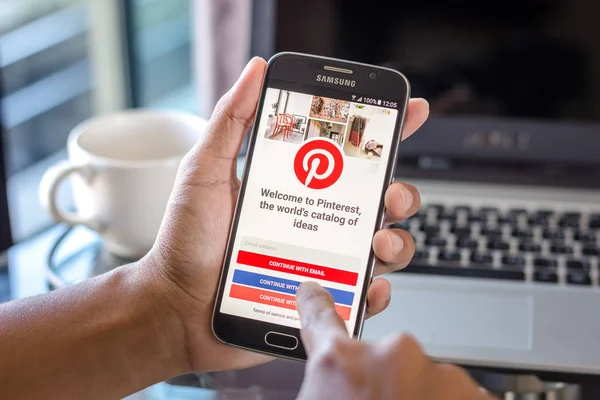 Chiang Mai, Tayland - 1 Şubat 2017: Asya adam Resepsiyon ofis üstünde belgili tanımlık perde üzerinde pinterest uygulaması ile Samsung Galaxy S6 tutarak. İş çalışma alanı'nın Üstten Görünüm.