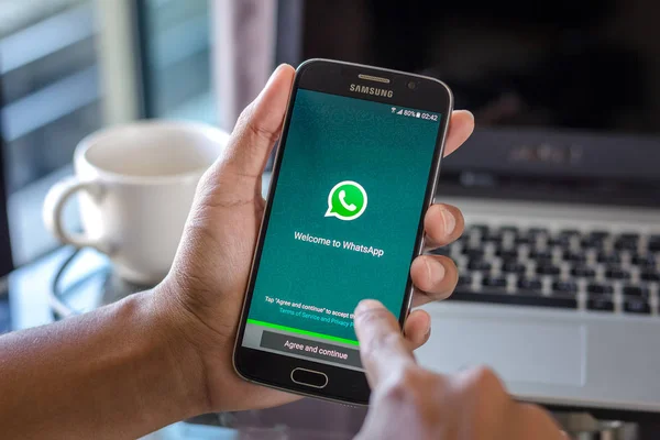 Chiang Mai, Tayland - 1 Şubat 2017: Asya adam whatsapp app üstünde belgili tanımlık perde Resepsiyon Office ile Samsung Galaxy S6 tutarak. İş çalışma alanı'nın Üstten Görünüm.