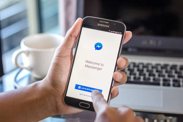Chiang Mai, Tajlandia - 1 lutego 2017: Asian Mężczyzna trzymając Samsung Galaxy S6 z aplikacji facebook messenger na ekranie na biurko biuro. Widok z góry business Workplace. — Zdjęcie stockowe