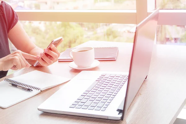 Close Up of woman hands using mobile phone and laptop computer with blank copy space screen for your advertising text message or content business in the Vintage effect.