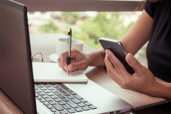 Close Up of woman hands using mobile phone and laptop computer with blank copy space screen for your advertising text message or content business in the Vintage effect.