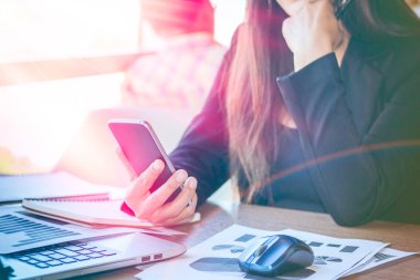 Bir smartphone ve bir dizüstü bilgisayar ile bir belgeyle bir kahve dükkanında çalışan kadar yakın işadamları.