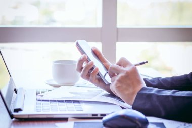 Bir smartphone ve bir dizüstü bilgisayar ile bir belgeyle bir kahve dükkanında çalışan kadar yakın işadamları.