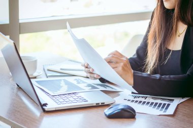 Bir smartphone ve bir dizüstü bilgisayar ile bir belgeyle bir kahve dükkanında çalışan kadar yakın işadamları.