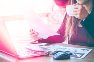 Bir smartphone ve bir dizüstü bilgisayar ile bir belgeyle bir kahve dükkanında çalışan kadar yakın işadamları.