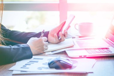 Bir smartphone ve bir dizüstü bilgisayar ile bir belgeyle bir kahve dükkanında çalışan kadar yakın işadamları.