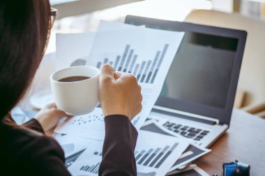 Bir smartphone ve bir dizüstü bilgisayar ile bir belgeyle bir kahve dükkanında çalışan kadar yakın işadamları.